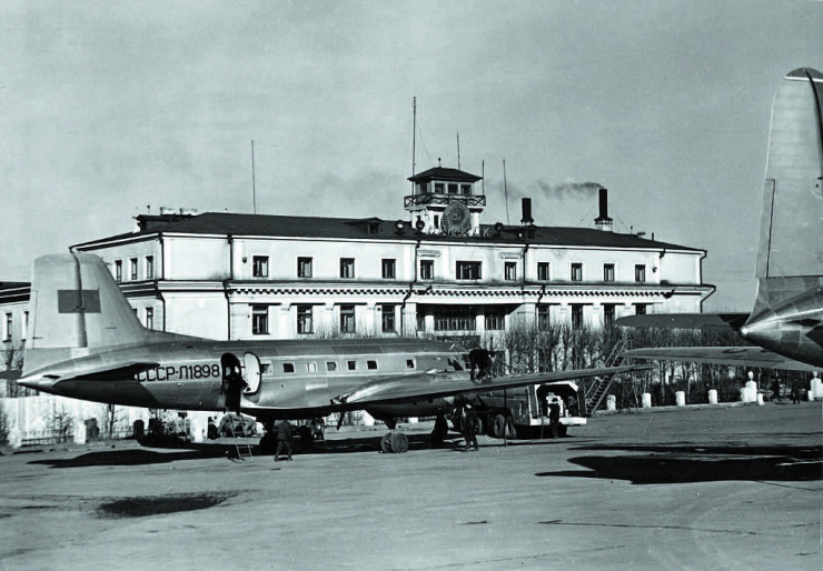 Иркутский аэровокзал построен в 1938 году (в 1960-м к зданию пристроят правое и левое крыла). Снимок символичен: справа виден киль пассажирского Ил-12 (прибыл в Иркутск в мае 1951 года), а заправляется топливом его «сменщик» Ил-14 (поступил к нам в ноябре 1954 года).