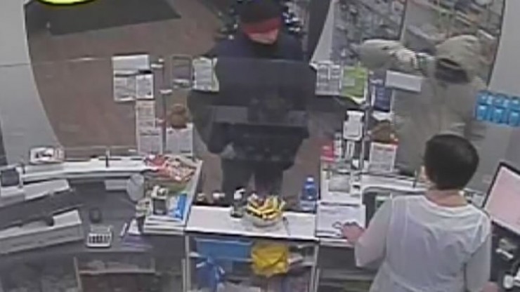Момент преступления в аптеке, запечатленный камерой видеонаблюдения. Грабитель справа в куртке с капюшоном.